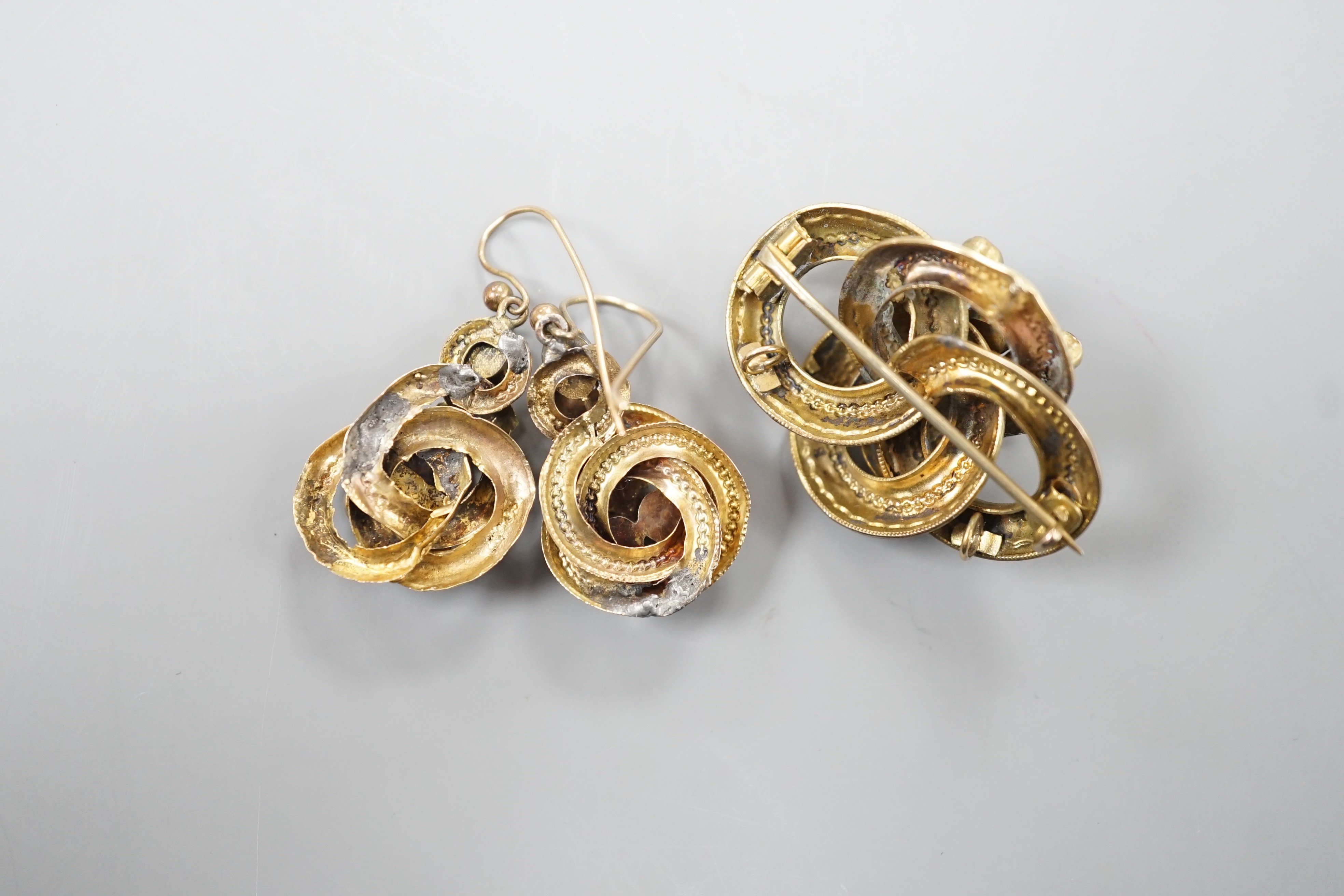 A Victorian yellow metal, oval and round cut garnet set demi parure, comprising a scroll work brooch and pair of matching earrings(a.f.), brooch, 38mm, gross weight 14 grams.